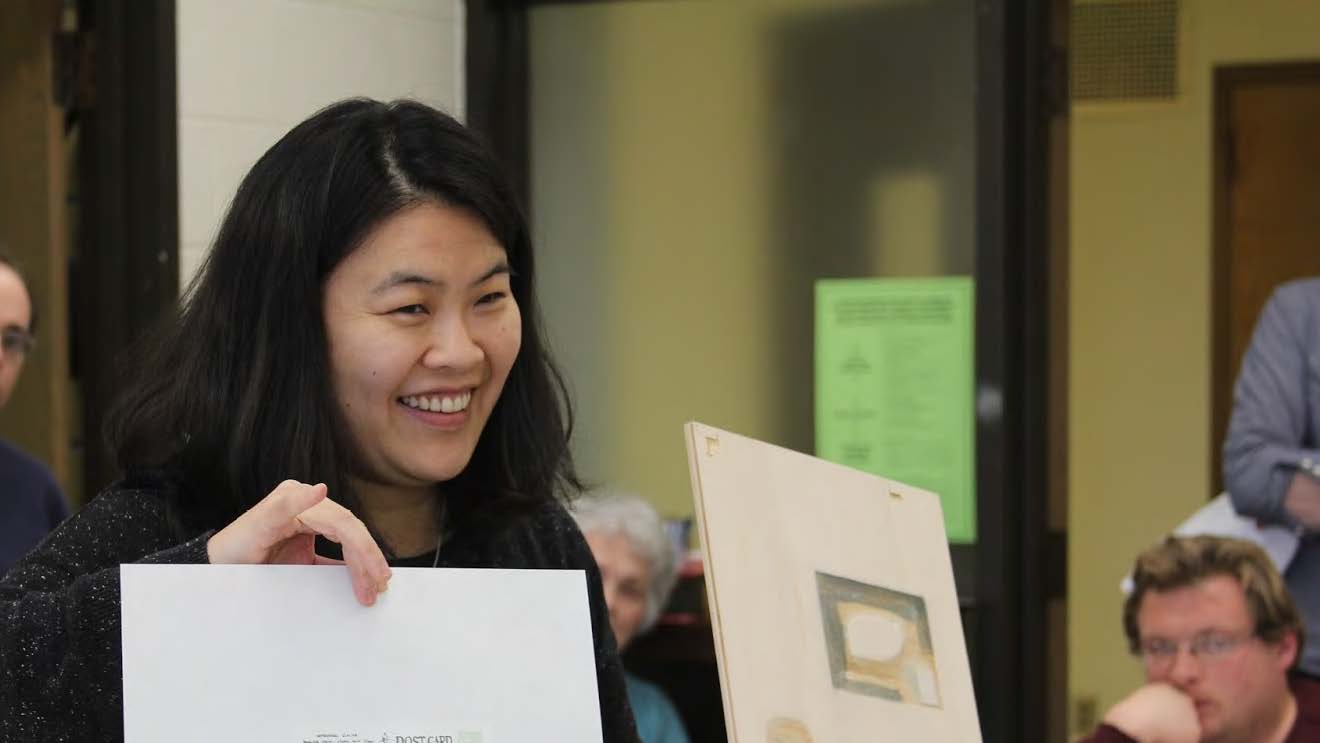 Professor Yoonmi Nam holds up a print at a critique