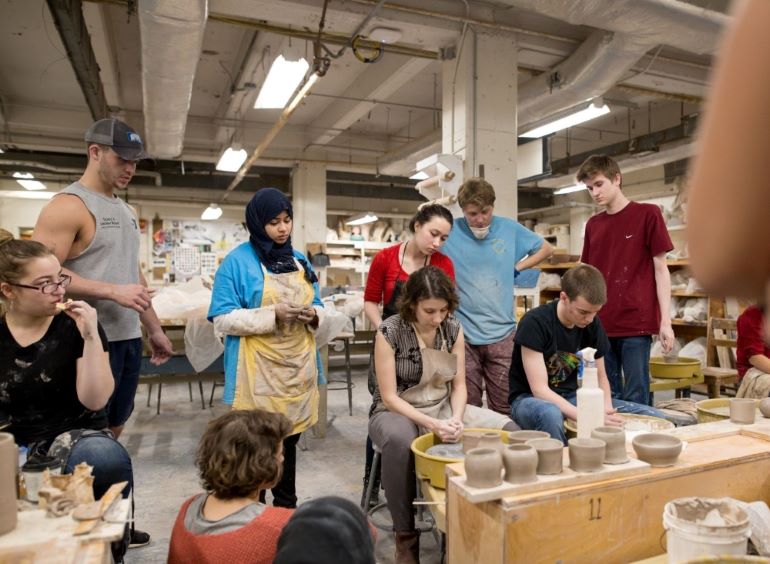 A ceramics class works at spinning wheels