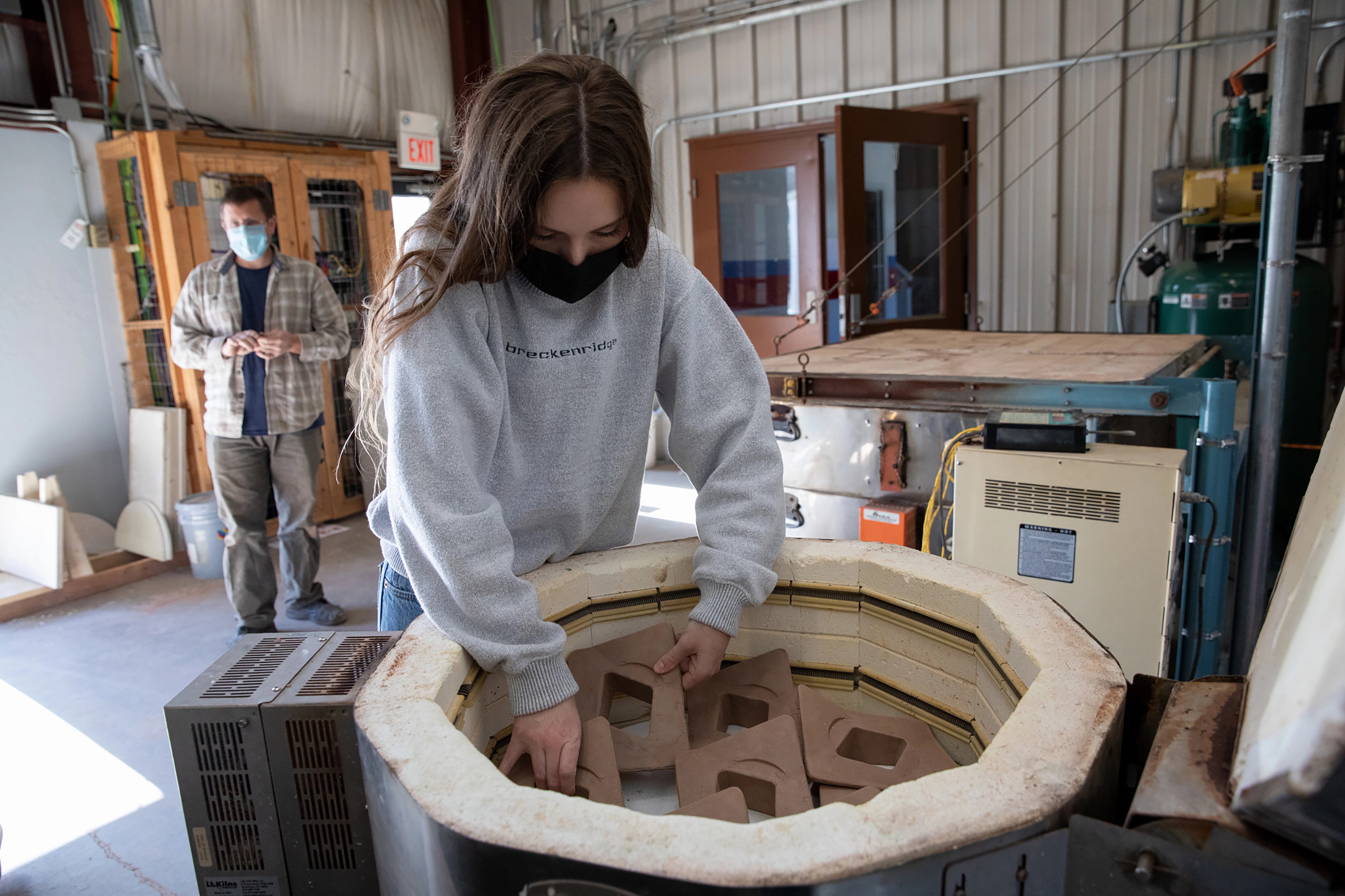 A student loads a kiln with terracotta tiles