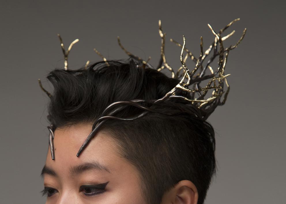 A model wears a branch like crown. The tips are bright gold and it gets darker and more patinaed as it nears the wearer.